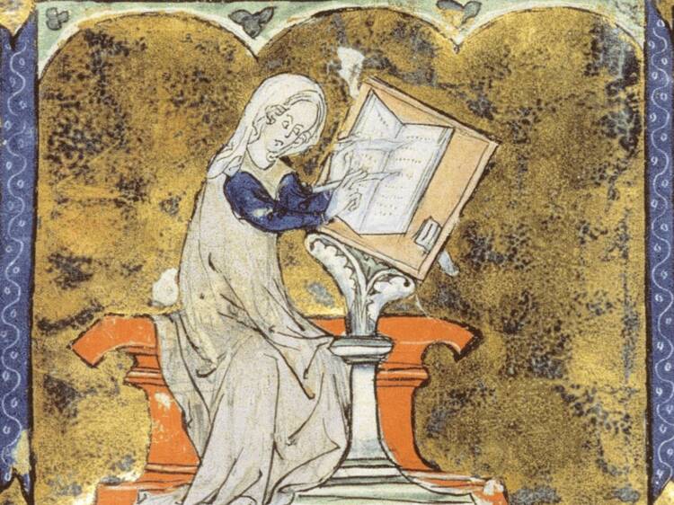 Marie de France mekossaan ja huivissaan koristeellisen pöydän ääressä kirjoittamassa kirjaan.